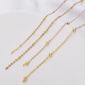 Macro shot of gold-plated copper chain extensions with polished beads for DIY jewelry