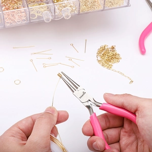 Macro view of pink handle round nose pliers shaping gold wire for jewelry making