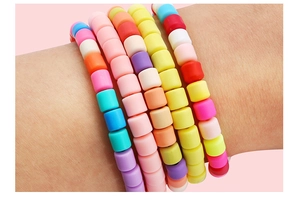 Detailed view of colorful 6mm polymer clay cylinder beads set on stacked elastic bracelets