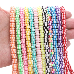 Macro detail of colorful striped polymer clay disc beads held in hand for DIY jewelry making