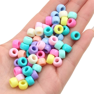 Macro view of macaron color acrylic cylinder beads held in hand for DIY size reference