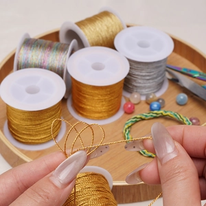 Metallisches Stickgarn-Spulen in Gold, Silber und Regenbogenfarben auf Holztablett