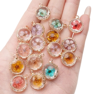 Detailed macro of 18K gold-plated resin pendants with real dried flowers in hand