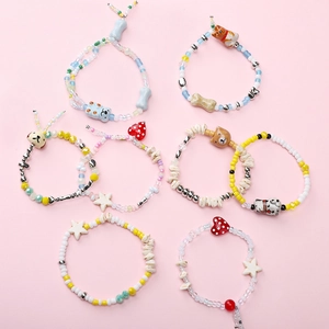 Flat lay of eight DIY beaded bracelets with cute puppy charms on a pink background