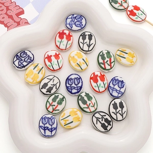 Macro view of colorful hand-painted tulip ceramic beads in a white flower-shaped dish