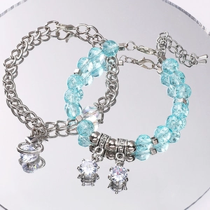 Détail de pendentifs clé cœur sur bracelets en argent et perles bleu clair
