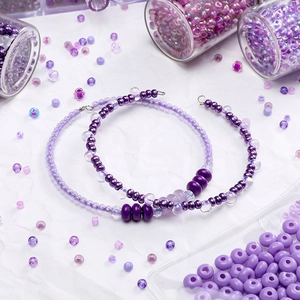 Detailaufnahme handgefertigter lila Perlenarmbänder und verschiedener DIY-Glasperlen-Zubehör