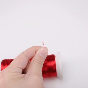 Close-up of bright red silk-like polyester thread for DIY jewelry making on a white spool