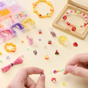 DIY jewelry kit with colorful clay fruit beads and letter charms in a plastic box
