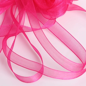 Gros plan sur ruban organza rose rouge avec texture semi-transparente et bords surjetés fins