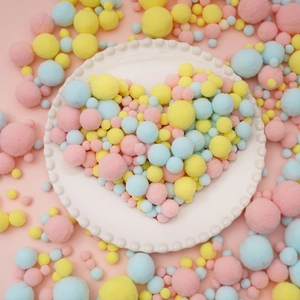 Colorful plush pom-poms arranged in a heart shape on a decorative white porcelain plate