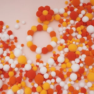 Detailed view of colorful high-elastic polyester pompoms in orange, yellow and white