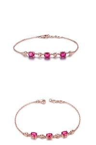 Détail d'un bracelet en or rose avec trois pierres rouges ovales et fermoir mousqueton