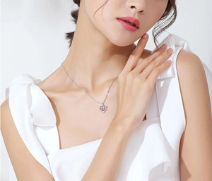 Close-up of heart-shaped pink crystal pendant necklace worn by a female model