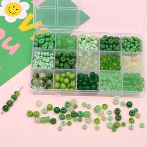 Macro shot of a 15-grid organizer box filled with various green DIY glass crystal beads