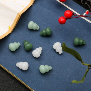 Detailed view of polished glass gourd beads in white and green for DIY jewelry making