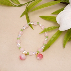 Close-up of beaded bracelet with pink peach charms and mixed pastel glass beads
