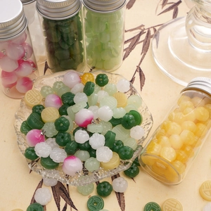 Assorted DIY jewelry beads and charms with traditional Chinese motifs in storage bottle