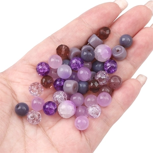 Assorted purple and brown glass beads for DIY jewelry making displayed on a hand