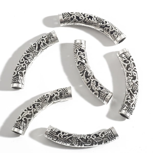 Macro detail of six antique silver hollow curved tube beads with intricate floral carving