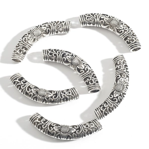 Macro detail of hollow vintage silver alloy curved tube beads with sunflower embossing