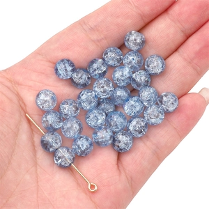 Detailed macro view of light blue crackle glass beads and gold headpin for DIY jewelry