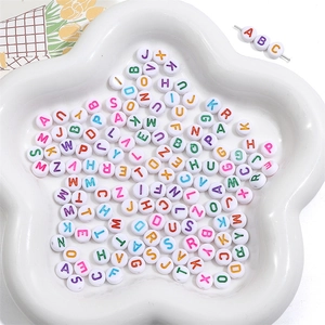 Macro shot of colorful acrylic alphabet letter beads on a white ceramic flower plate