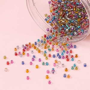 Colorful silver-lined glass seed beads scattered on pink surface for DIY jewelry making