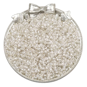 Pile of transparent glass seed beads in an elegant silver tray for DIY jewelry making