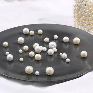 Macro shot of assorted size white imitation pearls in a black dish for DIY jewelry
