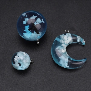 Detailed view of resin moon and bead charms with blue sky and white cloud patterns