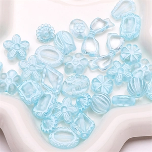 Macro shot of light blue acrylic DIY mixed beads with floral and ribbon patterns