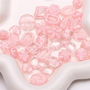 Detail of pink acrylic flower and bow beads for DIY jewelry making on white tray