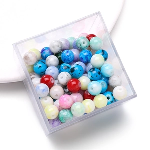 Detalle de cuentas redondas jaspeadas de colores en una caja de almacenamiento clara
