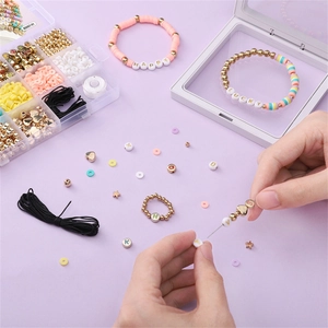 DIY jewelry kit with colorful clay beads, gold hearts, and letter charms in a 15-grid box