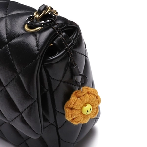 Black quilted shoulder bag with yellow crochet flower charm and polka dot strap