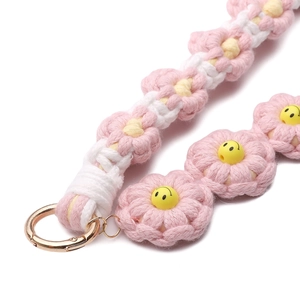 Close-up of pink woven daisy flower charm with smiley face and gold spring ring