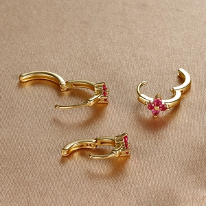 Detail of clover earrings with red zircon inlays and golden hoop closure design