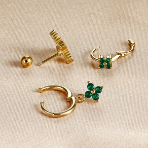 Detail of three-piece gold four-leaf clover earring set with green stones on silk