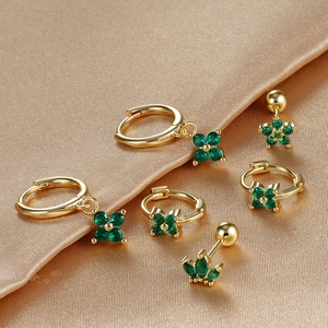 Elegant gold earrings set with green clover pendants on champagne silk background