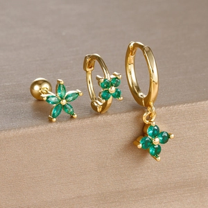 Macro shot of gold earrings set featuring green four-leaf clover charms and star studs