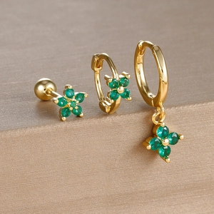 Detailed view of three-piece gold earrings set with green four-leaf clover crystals