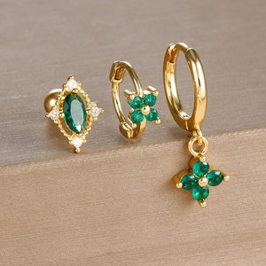 Macro shot of 3-piece gold clover earrings set with emerald green stones and zircons
