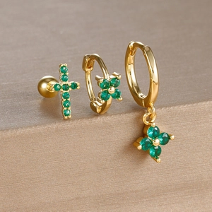 Detailed set of gold flower and cross earrings with green zircon stones on display