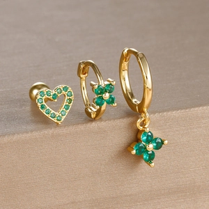 Detail of three gold earrings featuring green clover charms and heart zircon stones