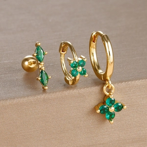 Detailed macro view of a 3-piece emerald green zircon and gold earring set on a stand