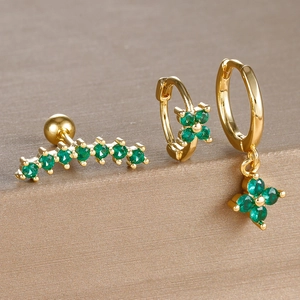 Detailed macro view of three-piece gold flower earring set with green gems