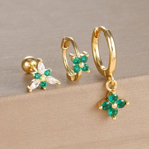 Detail of three-piece gold clover earring set with green and white crystals
