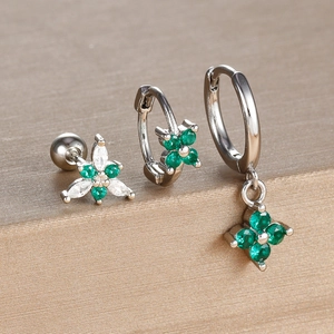 Macro detail of three-piece silver earring set with green clover cubic zirconia stones