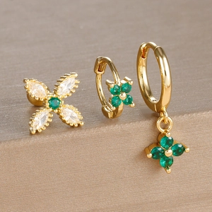 Detail of three-piece gold earring set with emerald green zircon clovers and star studs